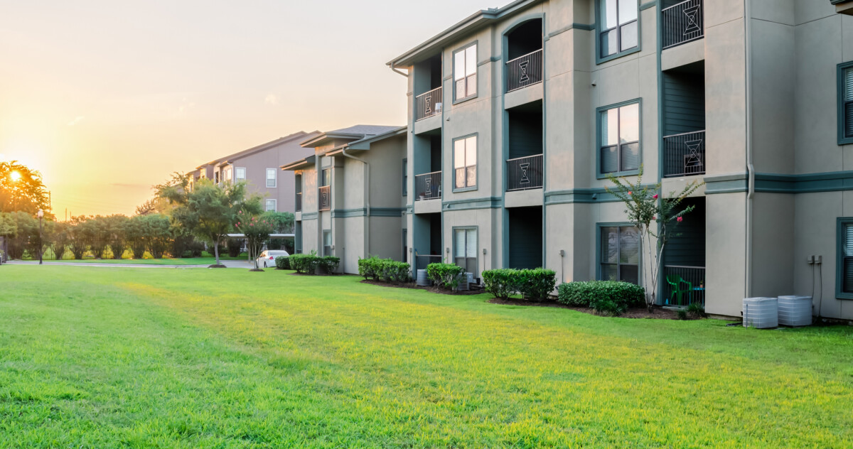 Apartment buildings overlooking a sunset and green field