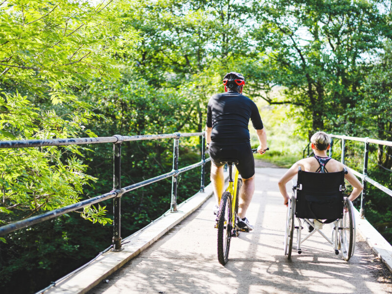 Person biking and person in wheel chair enjoying accessible community path